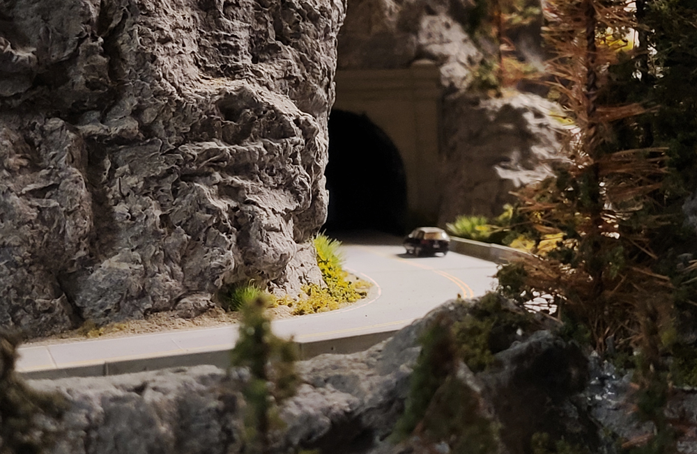 A photograph of a scale model car entering a tunnel on a model railroad layout