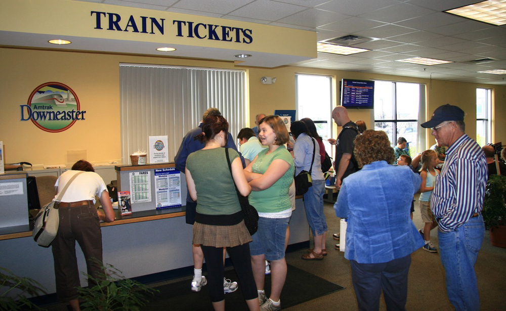 People gathered in front of counter with sign reading "Train Tickets"