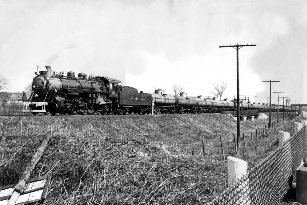 Steam Illinois Terminal locomotives with tank cars under bridge