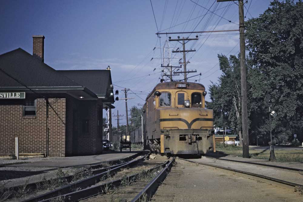 Yellow electric Illinois Terminal locomotives with train in front of brick station