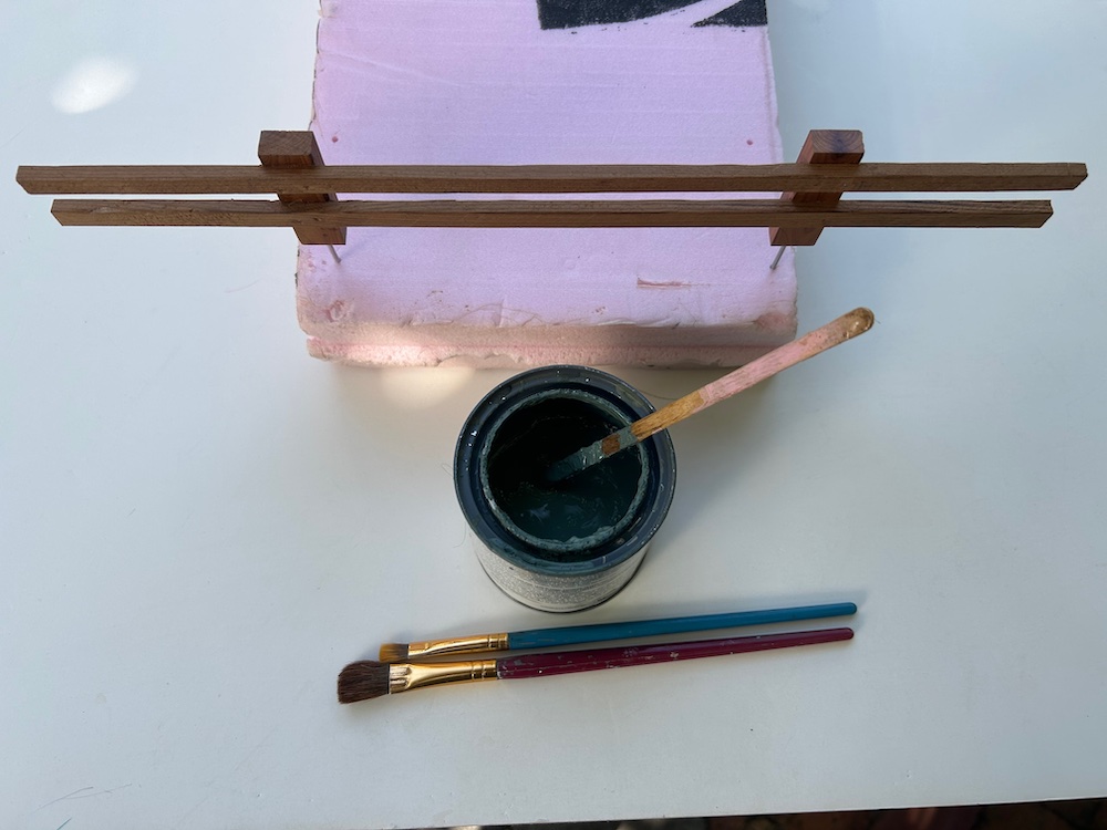 section of fencing with paintbrushes and container of stain