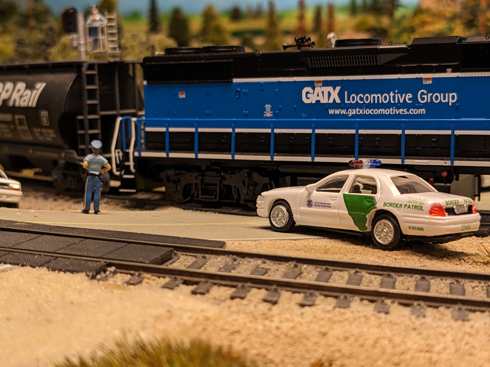 A model police figure and a model police figure next to a black model locomotive and black model tank car
