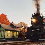 Steam and diesel locomotives next to a wooden depot