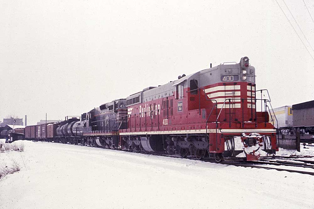 Burlington Route diesel locomotives one red and one black with freight train in snow