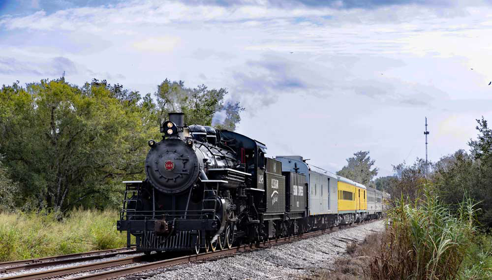 A color photograph of a steam locomotive pulling more modern passenger cars