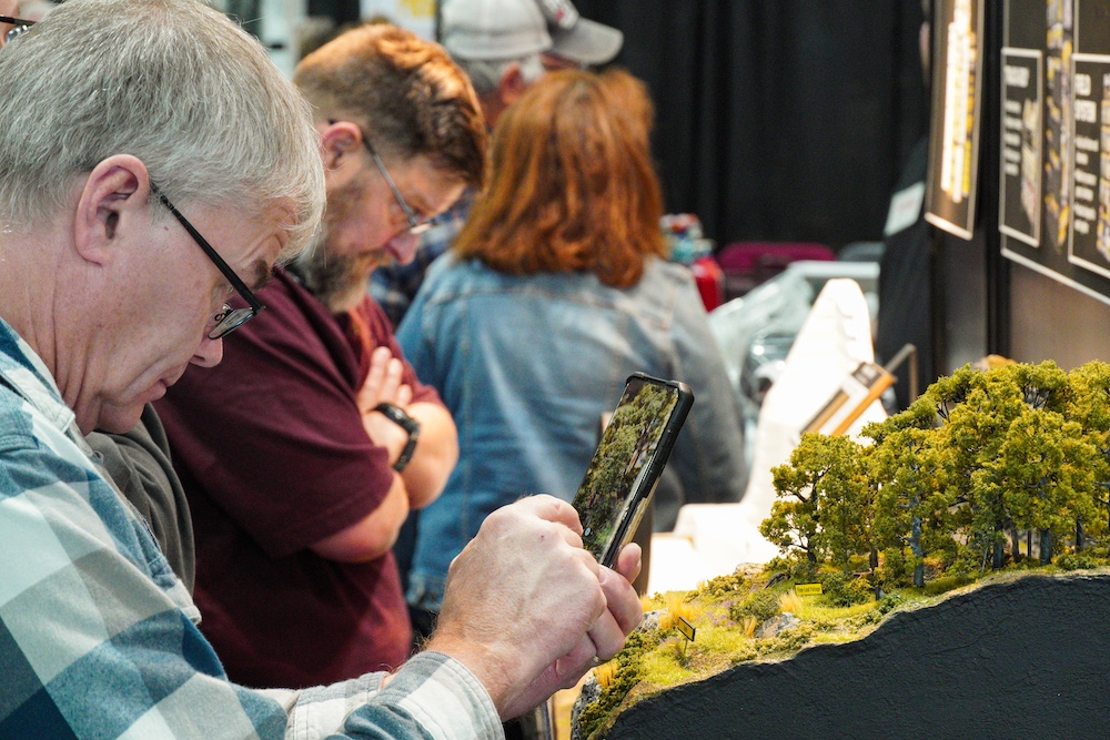 Train show attendee taking picture of displayed scenery