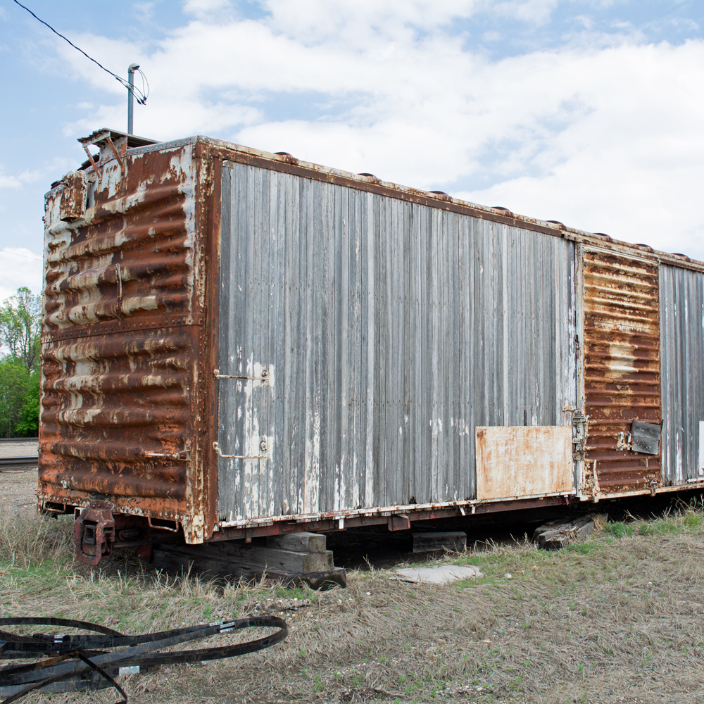 Color photo showing right side of heavily weathered wood and steel boxcar.