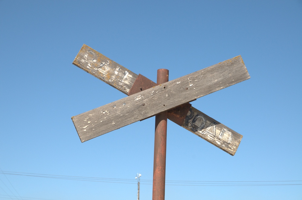 A worn wooden railroad crossing warning sign.