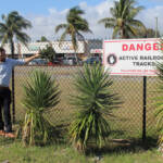 Two men next to fence with warning sign