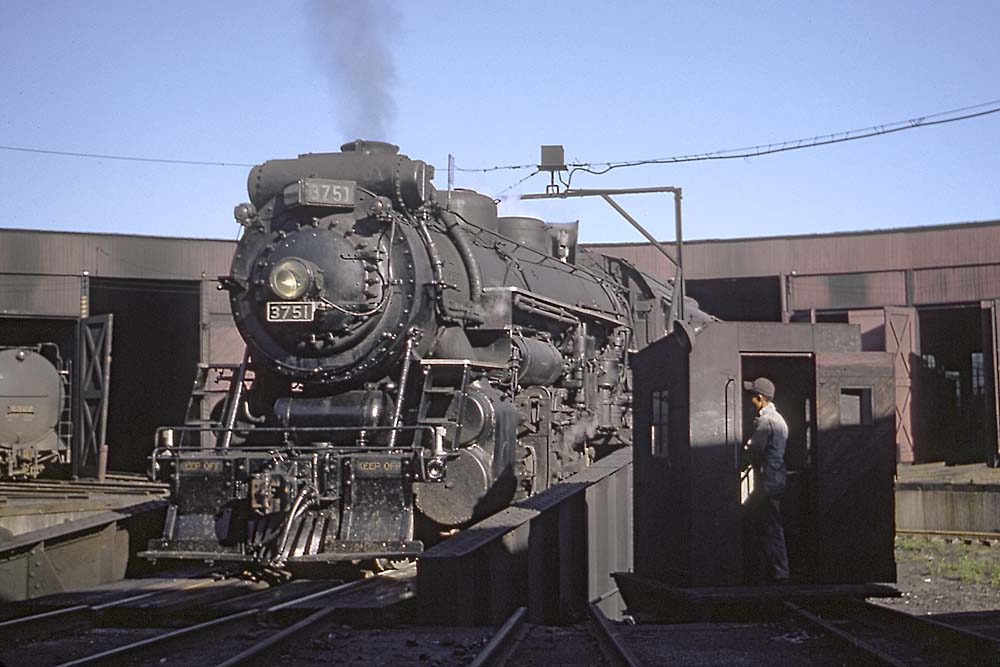 Grand Trunk Western steam locomotive on turntable by red wooden roundhouse