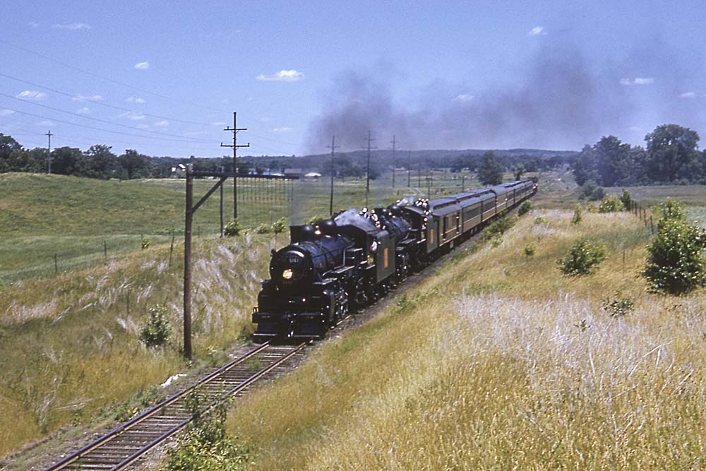 Two Grand Trunk Western steam locomotives on passenger train with people riding on tenders