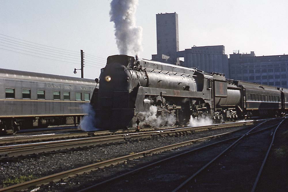 Streamlined smoking Grand Trunk Western steam locomotive with passenger train