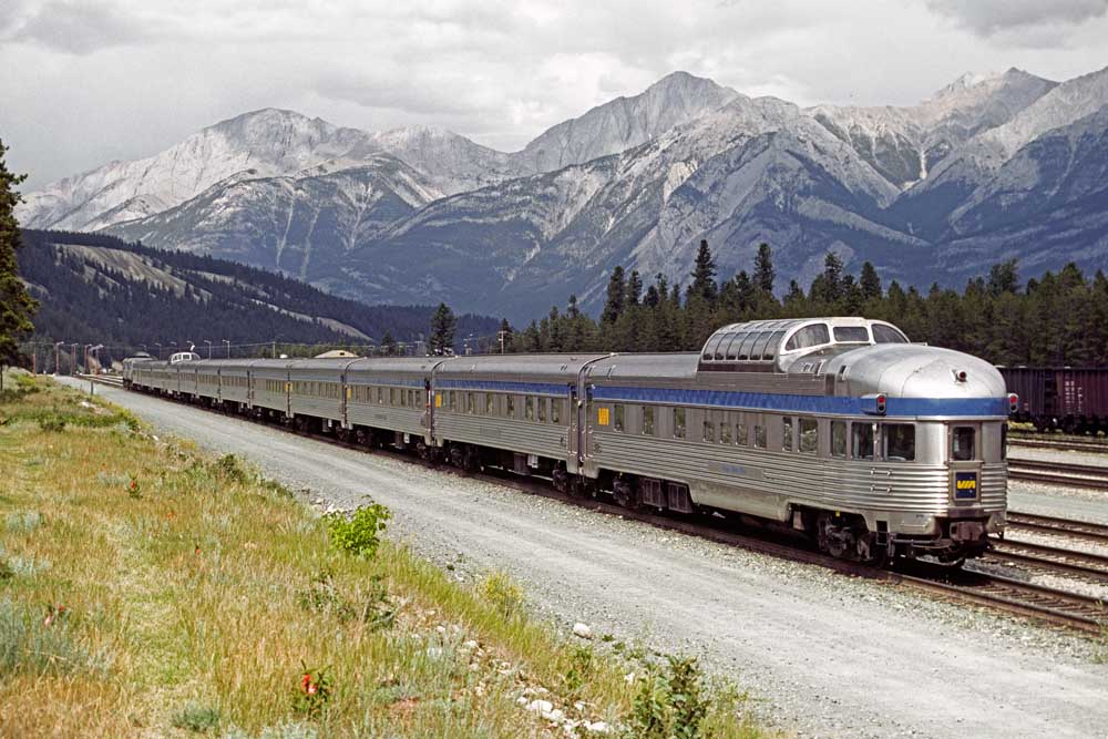 Stainless-and-blue streamlined passenger train set in mountain valley