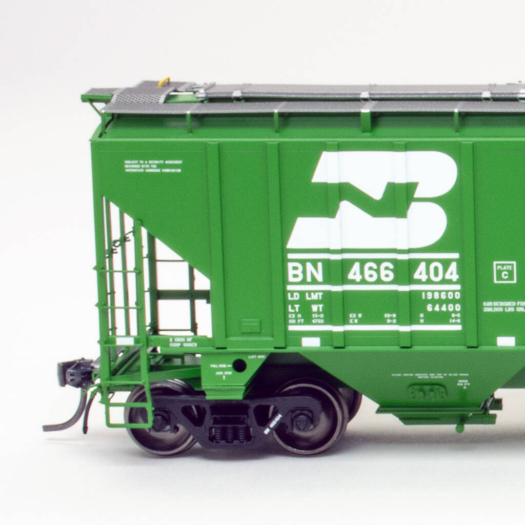 Side view of HO scale three-bay covered hopper painted green on white background.