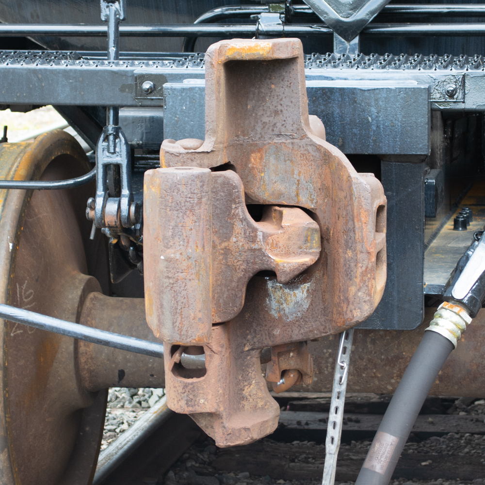Color photo of rusty coupler on freshly painted black tank car.