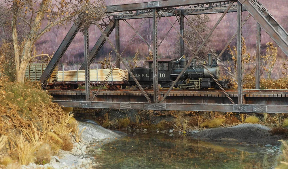 A model train crosses over a river on a bridge