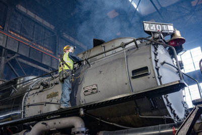 Worker inspecting Big Boy steam locomotive smoke stack.