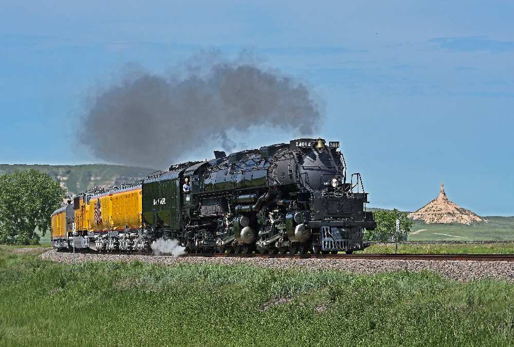Big boy steam locomotive and train traveling through a green hilly region. Union Pacific Big Boy Home Run Express.