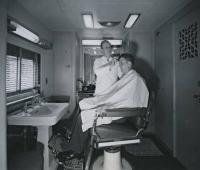 Man getting a hair cut aboard a Union Pacific passenger train. Five mind-blowing things no longer found on passenger trains.
