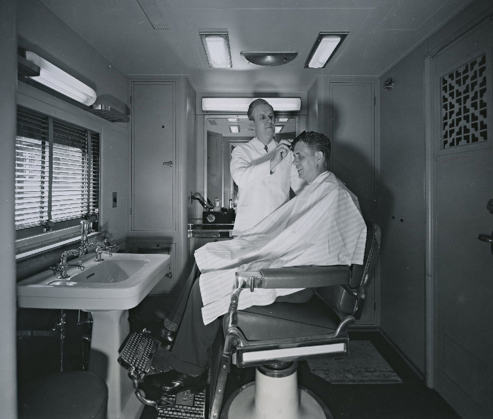 Man getting a hair cut aboard a Union Pacific passenger train.
