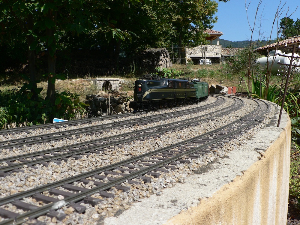 green locomotive on curve of garden railway
