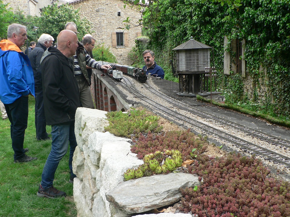 men standing next to garden railway, waiting trains