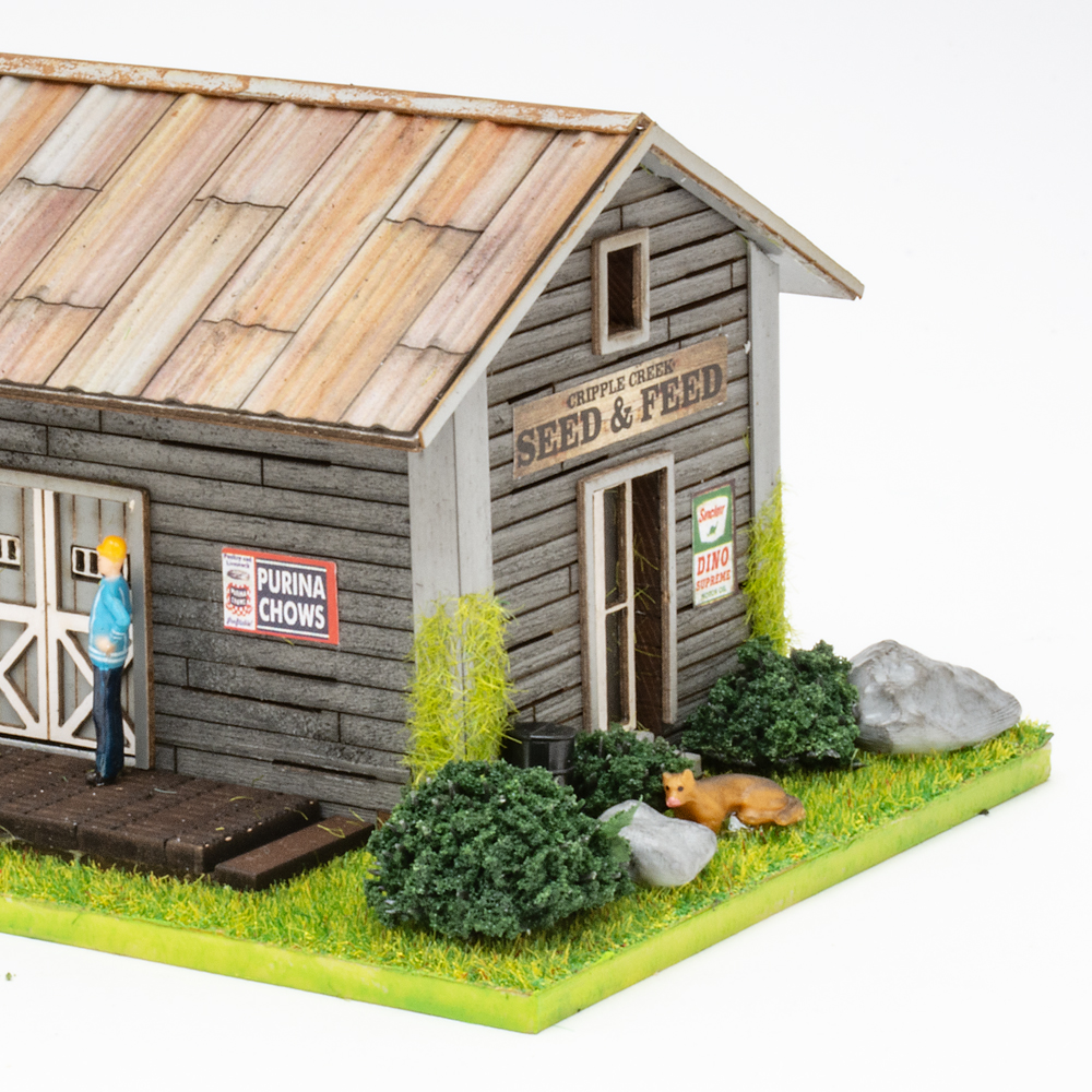 Color image of weathered gray HO scale building with scenicked base on white background.