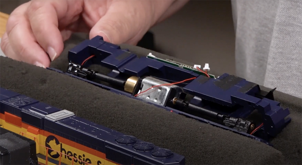 A hand manipulates a partially disassembled model locomotive