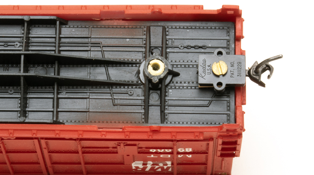 The underside of a red model freight car with coupler