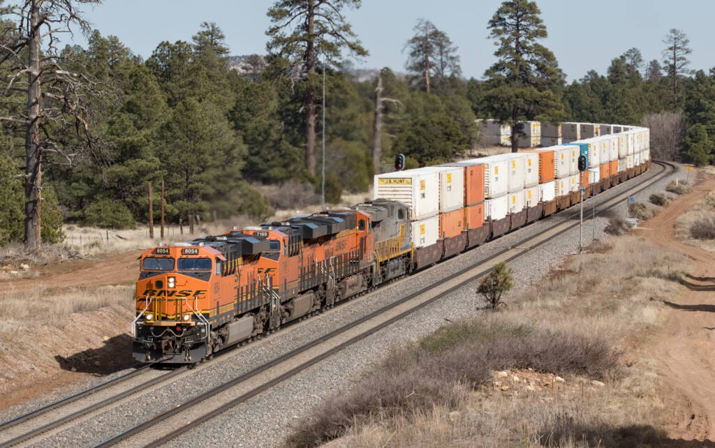 Four locomotives lead a doublestack train around a curve on a doule-track rail line