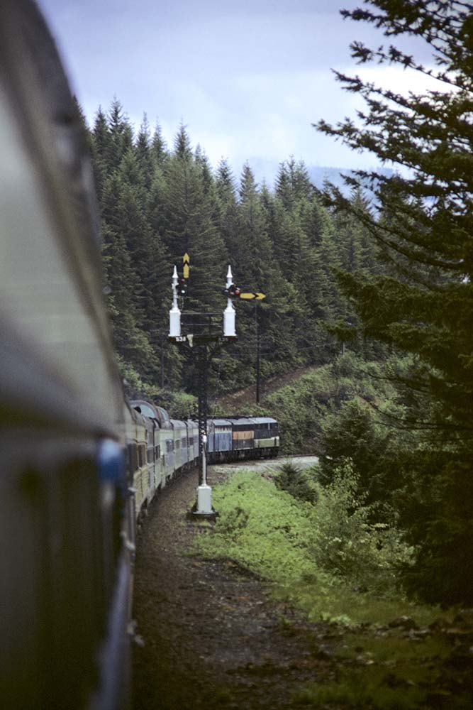Multi-colored passenger train with two-mast semaphore signals on curve