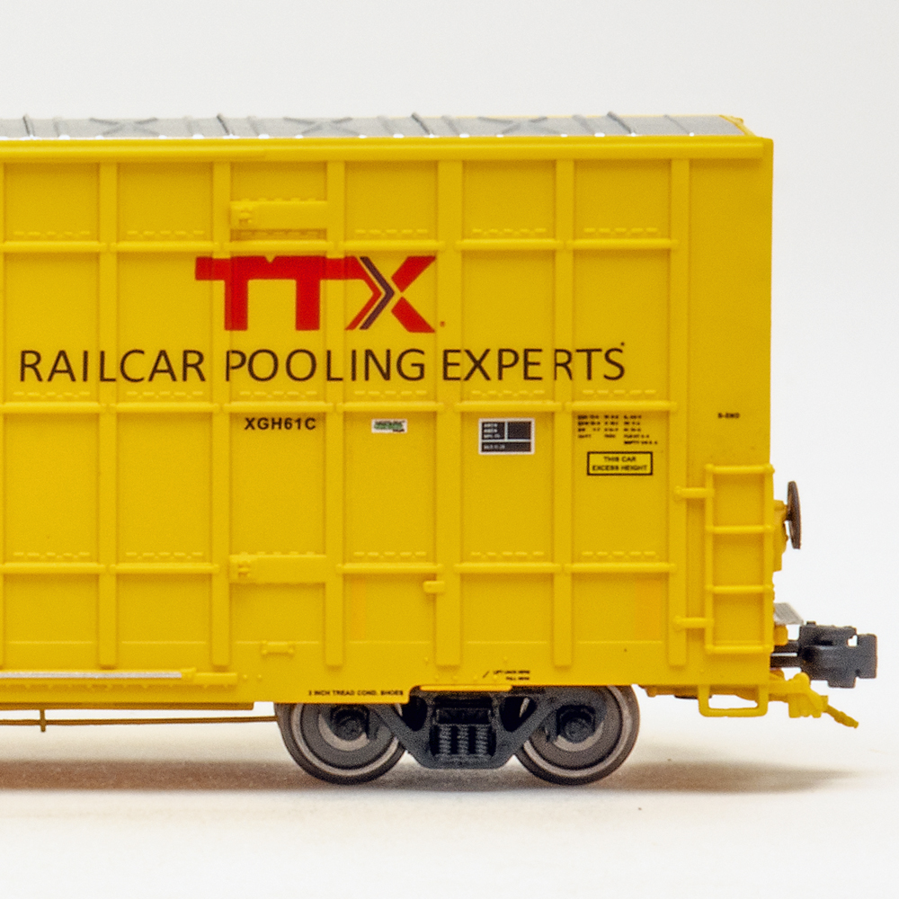 Side view of N scale boxcar painted yellow and black on white background