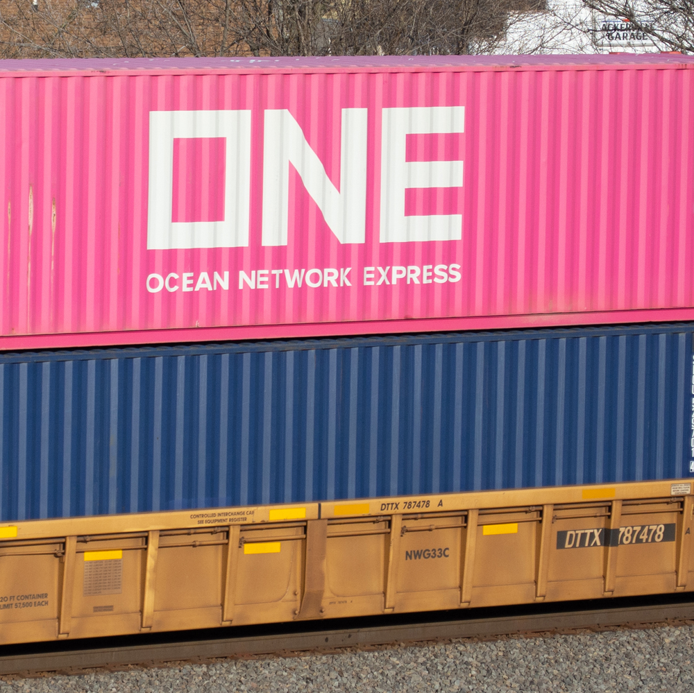 Color photo of weathered yellow well car with cherry blossom magenta and blue containers.
