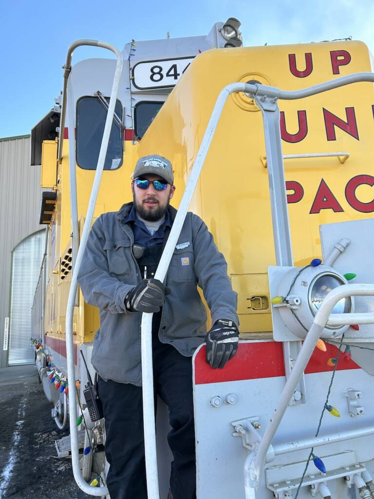 Young individual standing in front of a yellow diesel.