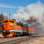 Orange locomotives with black and silver striping on passenger train