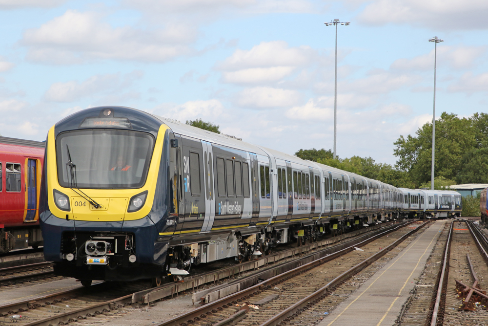Dark blue and gray EMU trainset with yellow nose parked in railyard.