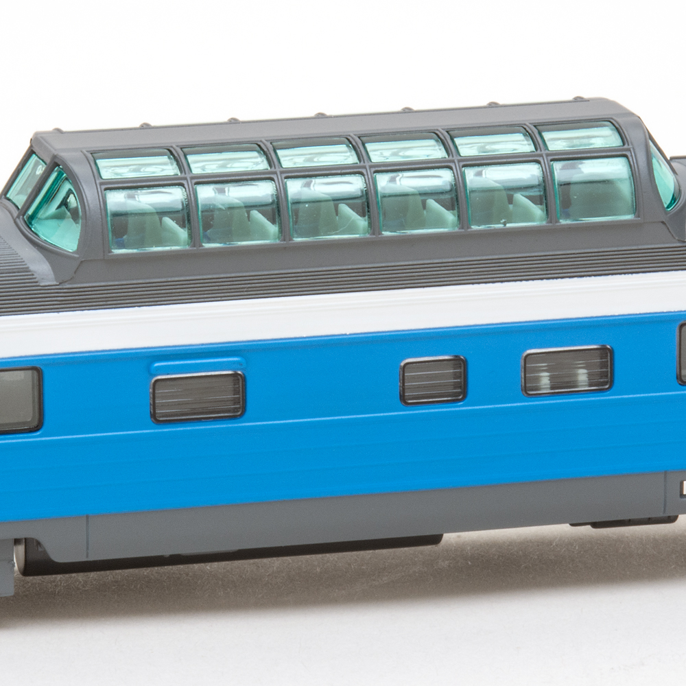 Color photo of N scale lightweight passenger car in blue, white, and gray paint.