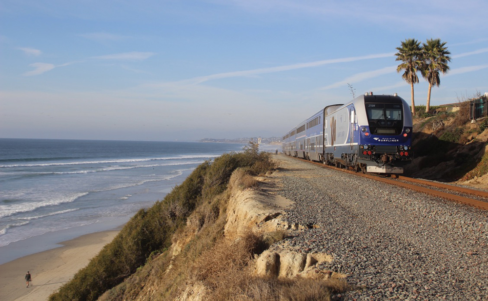 Passenger train on track on hillside above ocean
