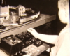 Black and white image with child near toy train layout
