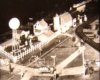 Black and white image on toy train layout with a house and cars