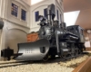 Low-angle shot of steam locomotive in front of a white building