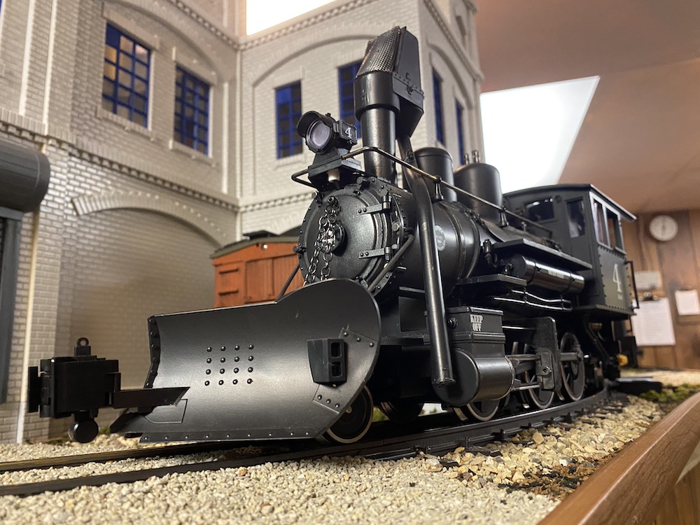 Low-angle shot of steam locomotive in front of a white building
