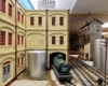 Large-scale green tank car sits near the entrance of a cream scratch-built building