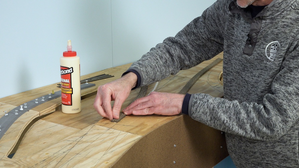Cork roadbed strip being glued onto tabletop