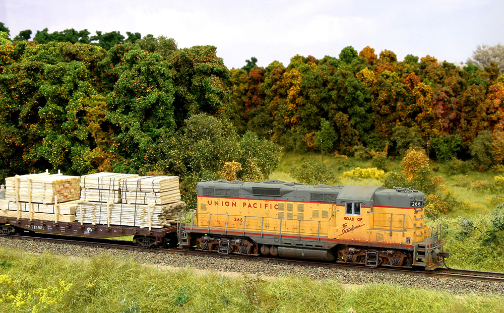 Color photo of HO diesel and freight car passing trees in fall colors.