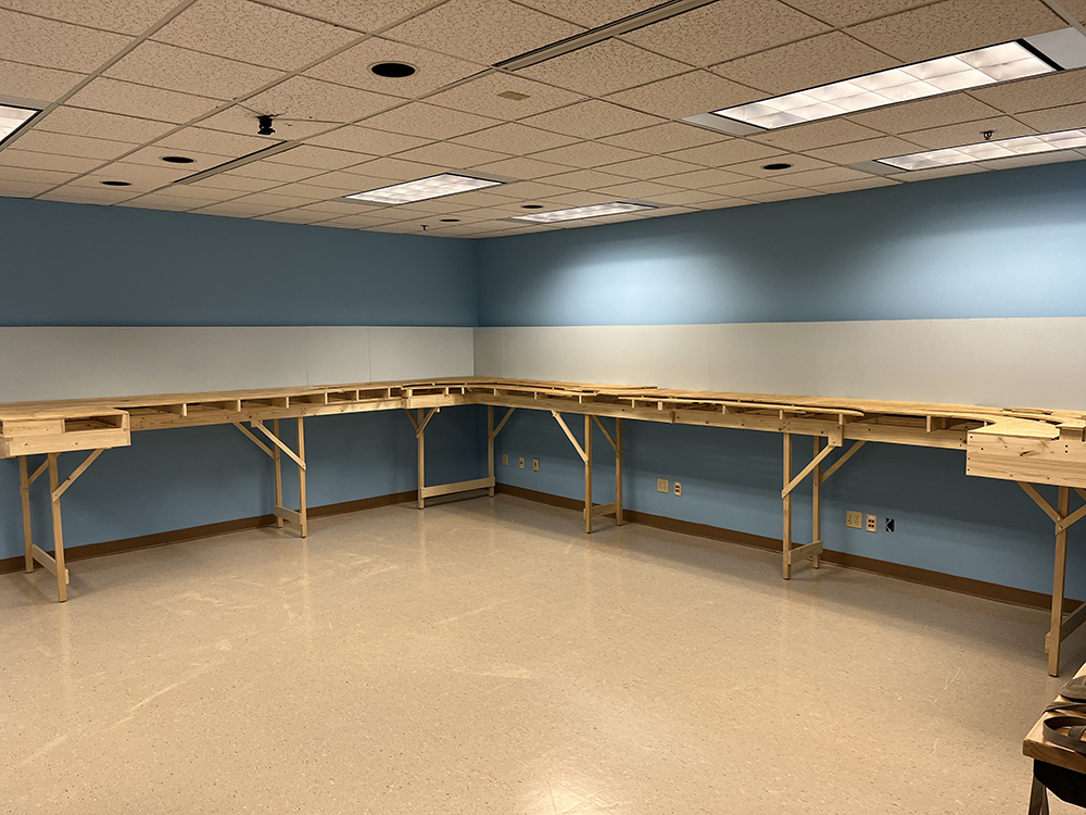 bare wood frames and legs arranged along two walls that will eventually support a model railroad.
