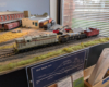 An HO scale GP7, gondola with pipe load, and caboose on a layout.