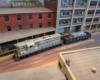 An HO scale GP7 and loaded gondola at a factory.