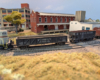 An HO scale GP7 with a gondola and hopper behind it