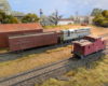 An HO scale GP7 picking up a boxcar from an industry with a caboose in front